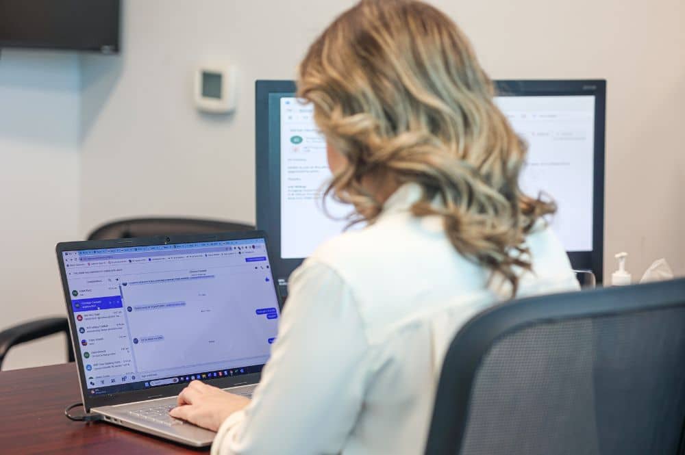 A woman working at a desk providing online patient support.