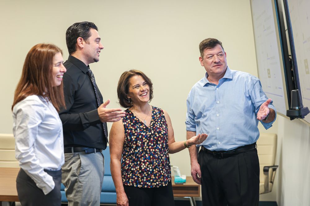 Pharmaceutical professionals discussing PAP coverage strategy at a patient access program meeting.