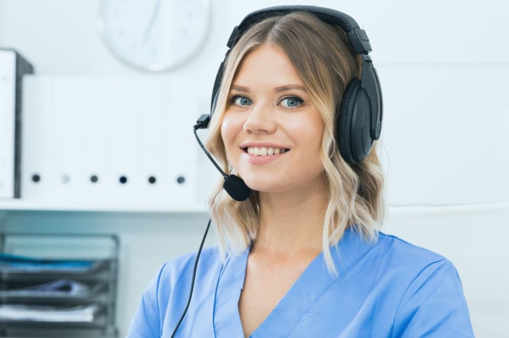 A woman in an office wearing a headset, engaged in flexible patient support platforms.