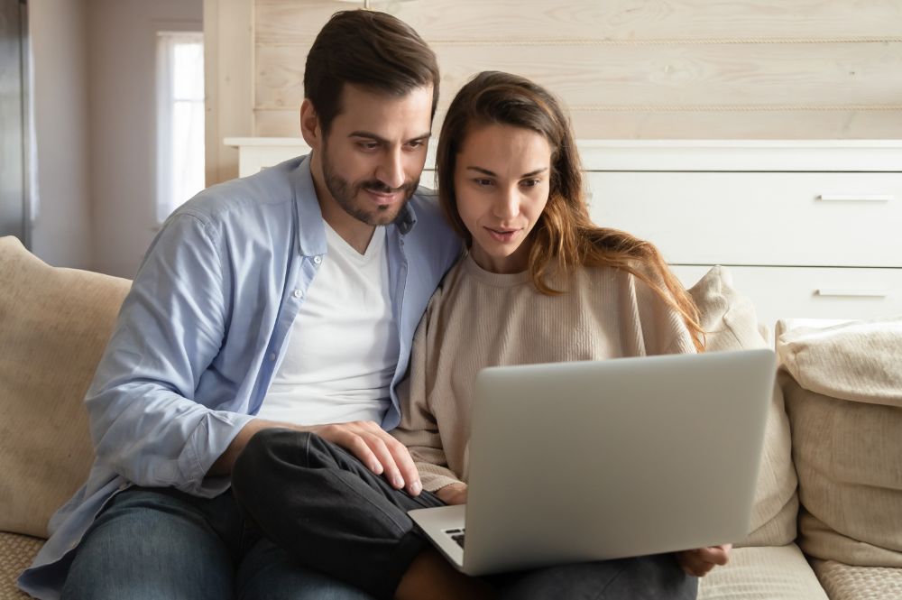 A man and woman on a couch, focused on a laptop, exploring patient recruitment technology together.