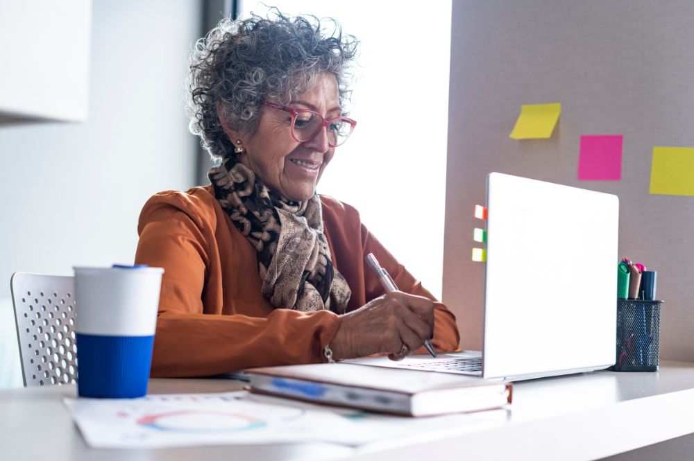 An older woman at a desk with a laptop, engaging with Digital PSP services.