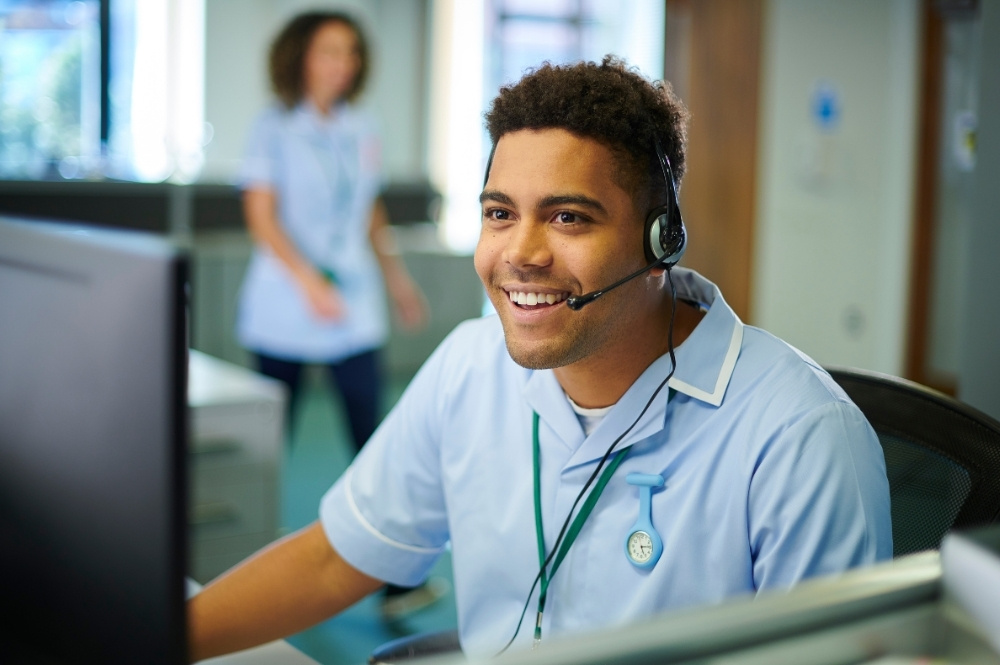 Smiling healthcare professional providing patient engagement services via headset to support clinical trial recruitment and retention.