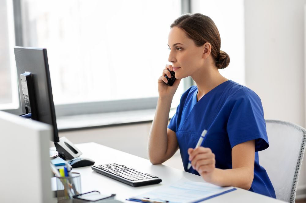 A woman in scrubs talking on the phone about Rare disease HCP referrals.