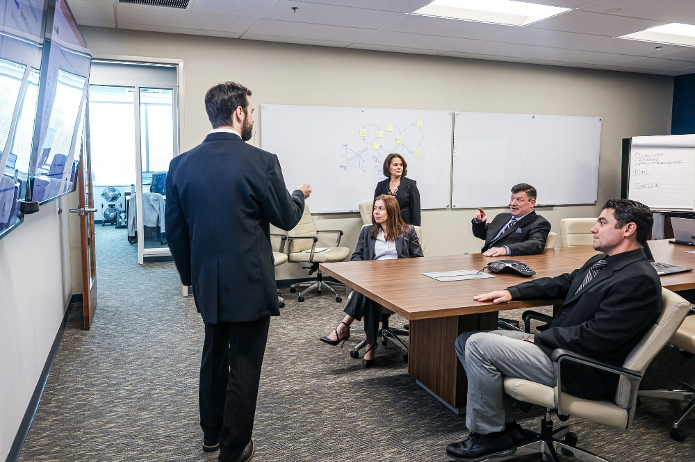 Business professionals in a strategy meeting reviewing real-time data on wall monitors