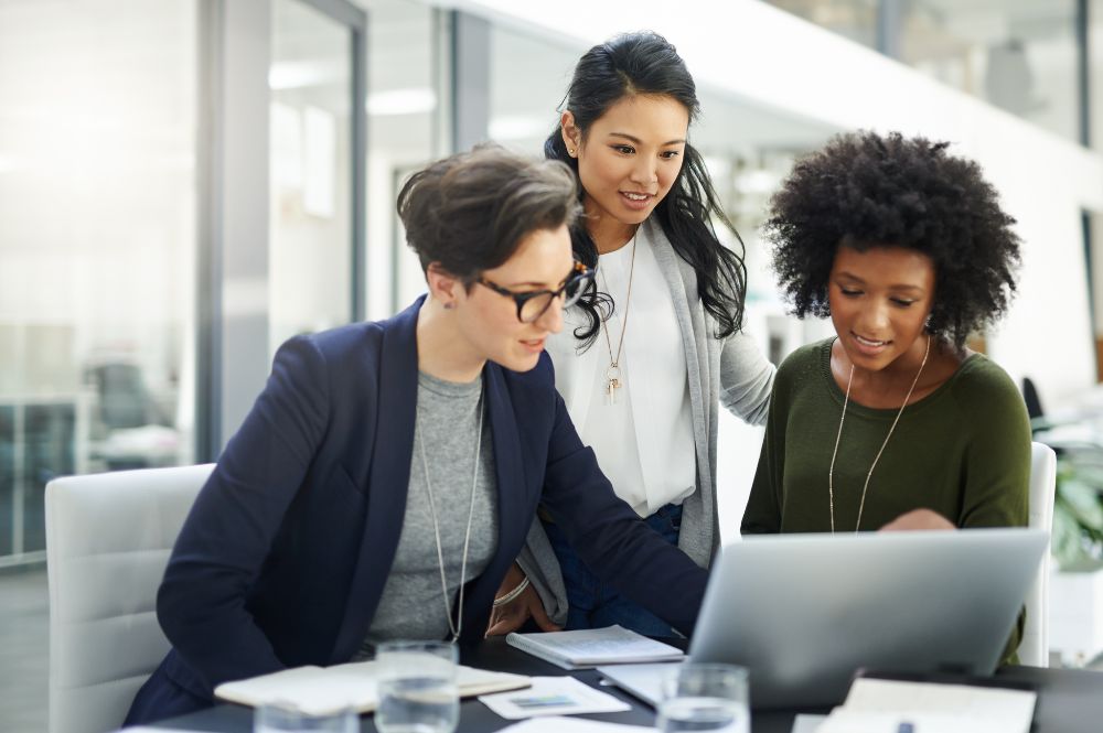 Three clinical professionals reviewing digital trial data on a laptop, illustrating digital health technologies in clinical research and decentralized trials.